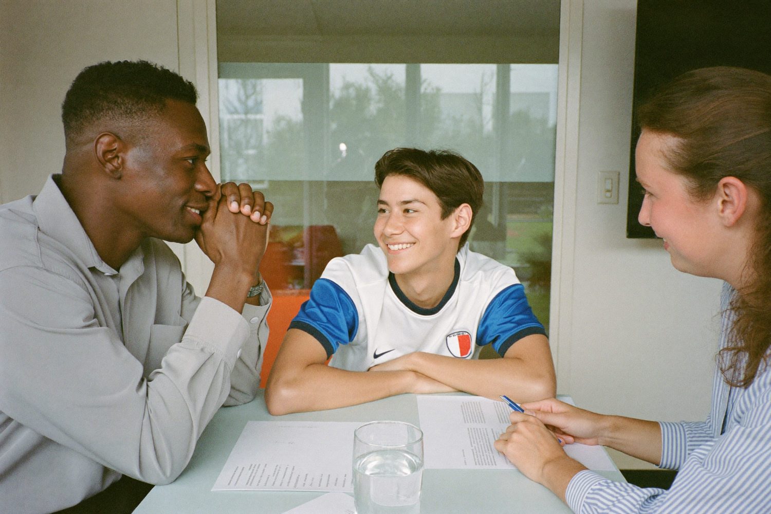 A Ripple Effect advisor reviewing a dual-credit plan with a student-athlete and their parent at a table